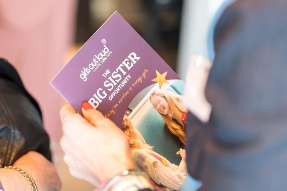 Woman holding a leaflet called 'The Big Sister opportunity'